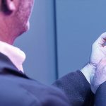 Ένα άτομο που φορά ακουστικά βαρηκοΐας τελευταίας τεχνολογίας και χρησιμοποιεί μια εφαρμογή στο κινητό του για να τα ρυθμίσει